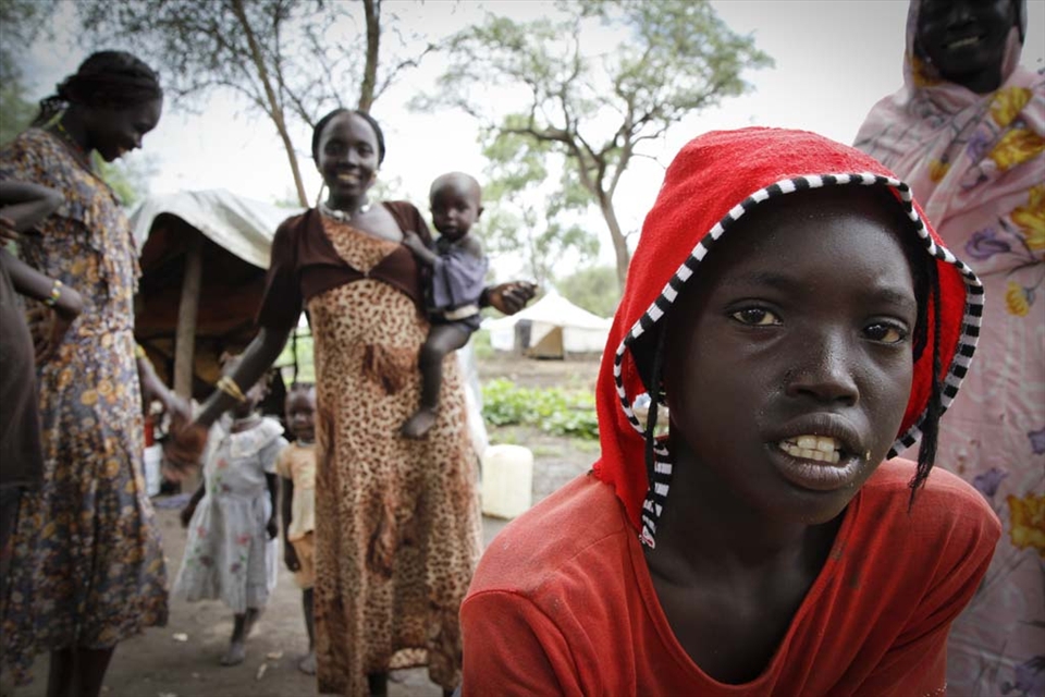 A girl stands with her family - she’s excited to go to the refugee camp school.