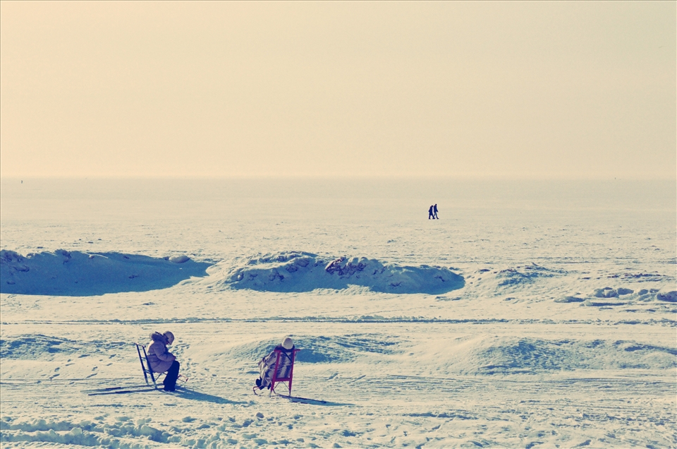 Two ladies taking the sun in the frozen beach of Saint Petersburg