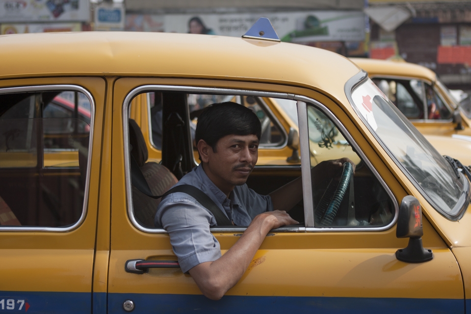 A driver of the typical yellow Kolkata taxis posing while in a traffic jam in Shyambazar area. 
