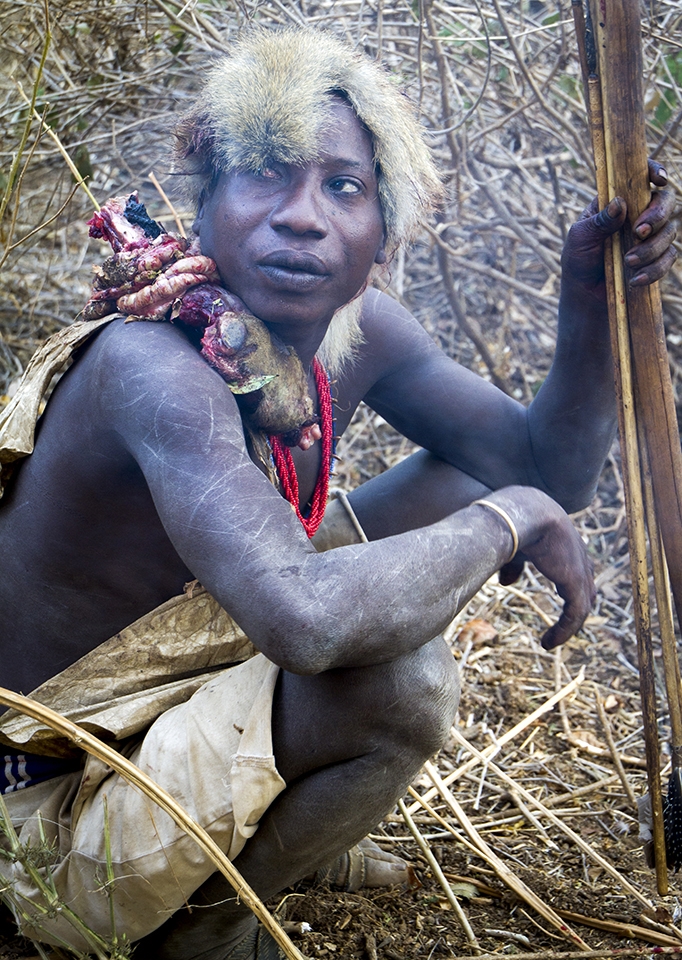 With primitive weapons in hand he wears sliver of monkey skin on his head.  