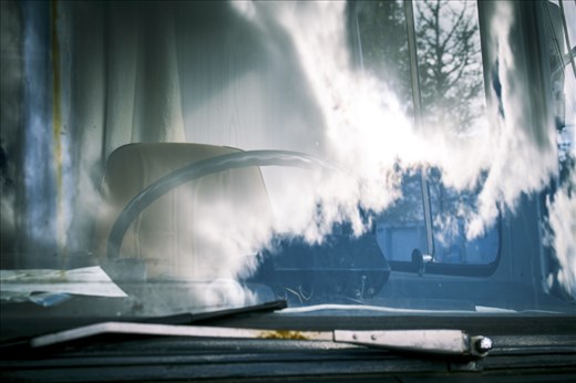 Clouds slowly race across the windscreen of a bus abandoned in the woods.
