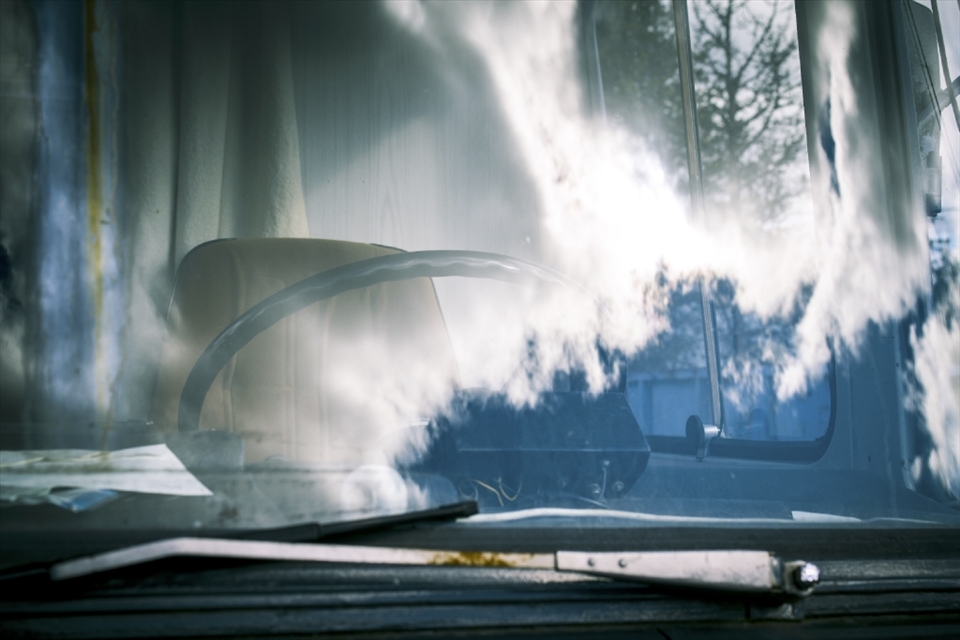 Clouds slowly race across the windscreen of a bus abandoned in the woods.