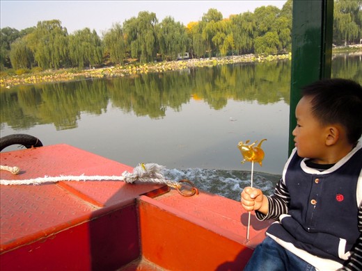 A little boy hold tightly onto his hand-made candy-on-a-stick as he enjoys a boat ride through the Summer Palace in Beijing. 