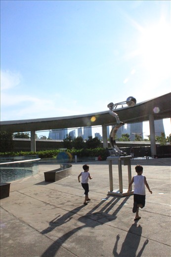 Pursuit of happiness. Two brothers play a simple game, chasing each other, the first person who passes the artwork will win. Beneath the bright blue sky, a perfect day to play.
 
