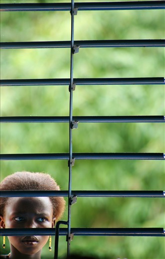 Toessè, Burkina Faso. A girl watching a protestant wedding from a window. 