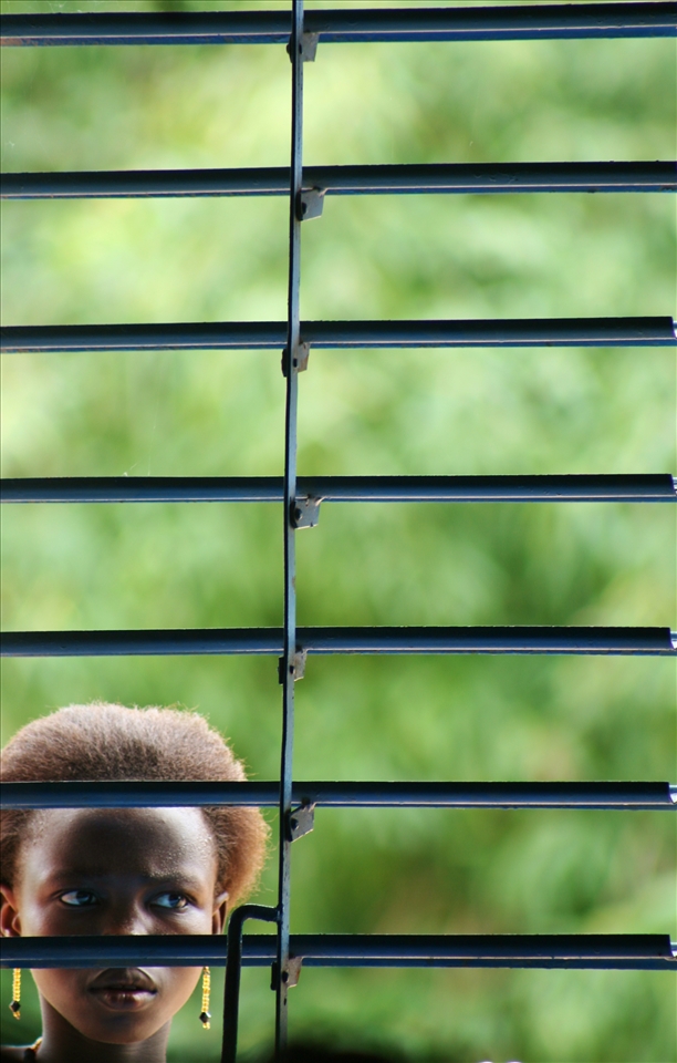 Toessè, Burkina Faso. A girl watching a protestant wedding from a window. 
