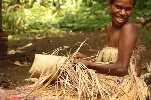 This young woman, living in a remote Kastom village in Tanna, where people still live according to millenary traditional customs, is weaving a basket with pandanus leaves. Lekalangia, Tanna, Vanuatu.