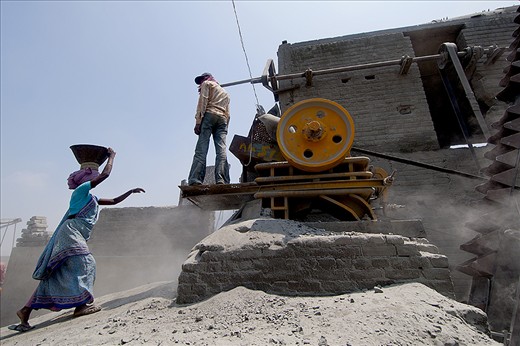 A women taking the stone to the crusher machine 