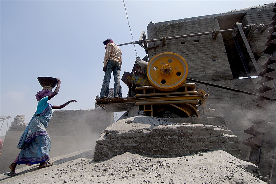 A women taking the stone to the crusher machine 