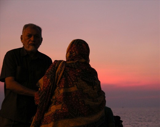 Mumbai is actually an island connected to mainland Maharastra by a series of roads. This is at the hook of Mumbai at Girgaum Chowpatty (Girgaum Beach). The whole stretch has this ongoing bench where hundreds of people come together and sit to see the beautiful pink, Bombay sunset and stay happily until twilight. I saw this man help his wife sit on the bench as it is a bit of an effort to get up.