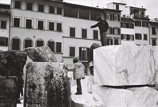 Children interact with each other while climbing the blocks, as parents keep watch. Florence, Italy.