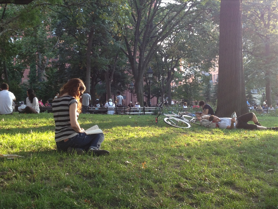 New York University's proximity to the park has caused students to adopt Washington Square Park as a de-facto quad. Here students enjoy reading outdoors one spring afternoon.