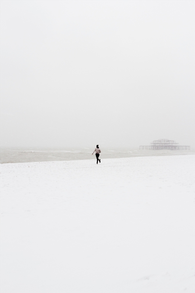 My friend Alistair and I were working together in Brighton when a sudden flurry of snow started falling down upon Brighton. On our lunch break we cut out of the office and headed to the beach. Once there, in a spontaneous moment, Alistair started running wildly towards the ocean, his arms aloft and waving in the excitement of the moment as the West Pier loomed in the background like an ominous shadow.
