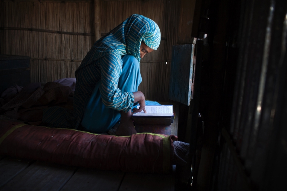 EAST GABGACHHI, BANGLADESH - August 2011. Shazeda Khatun (18) studying the Koran in her home in East Gabgacchi. She has been living on this char for 6 months after her family was forced to migrate when their home was eroded. The char island is extremely low lying and is susceptible to flooding during the monsoon season. 