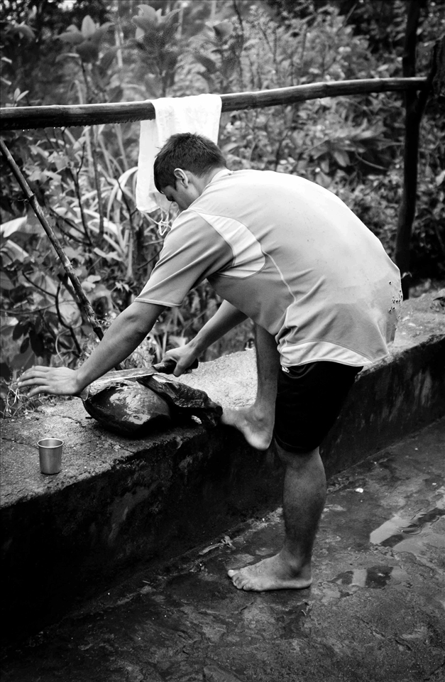 Saroj sharpens a machete before sacrificing a goat.
