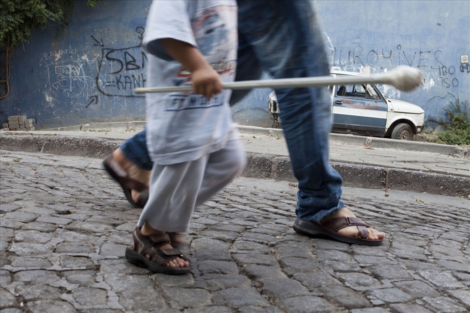 A boy proudly carries his older brother's circumcision scepter.