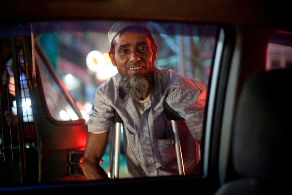 Happy beggar at private car window. Injured and unable to work, this man travels throughout the day and begs, always with a smile on his face.