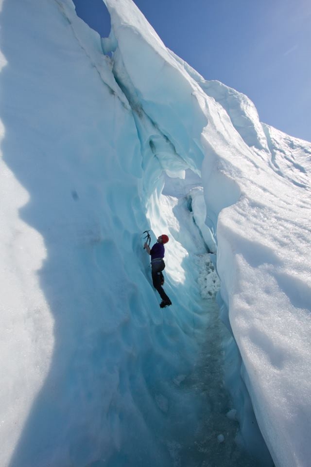 Brooklyn Fairchild ice climbs playfully in a cave on Matanuska Glacier.