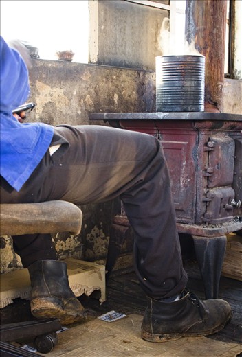 Inside the Kaapschehoop lookout post, watchman Nelson Matsewjwa uses a tin can to boil water on a wood stove, Mpumalanga, South Africa. Matsewjwa uses the water to make himself a cup of coffee; a much required caffeine boost for his 12 hour long shift.