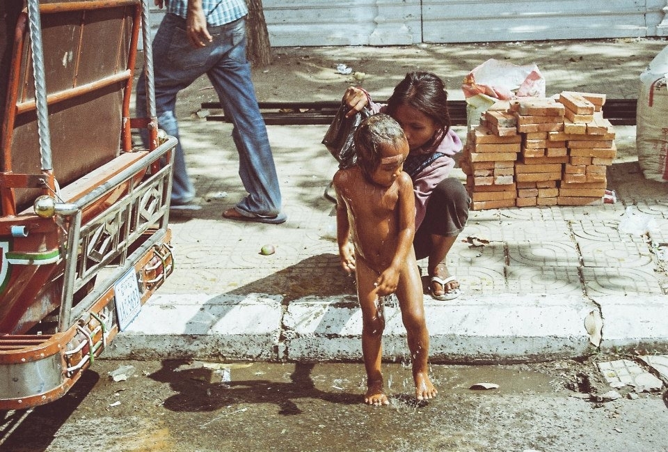Gypsy child having a shower on the Streets of Phnom Penh, Cambodia