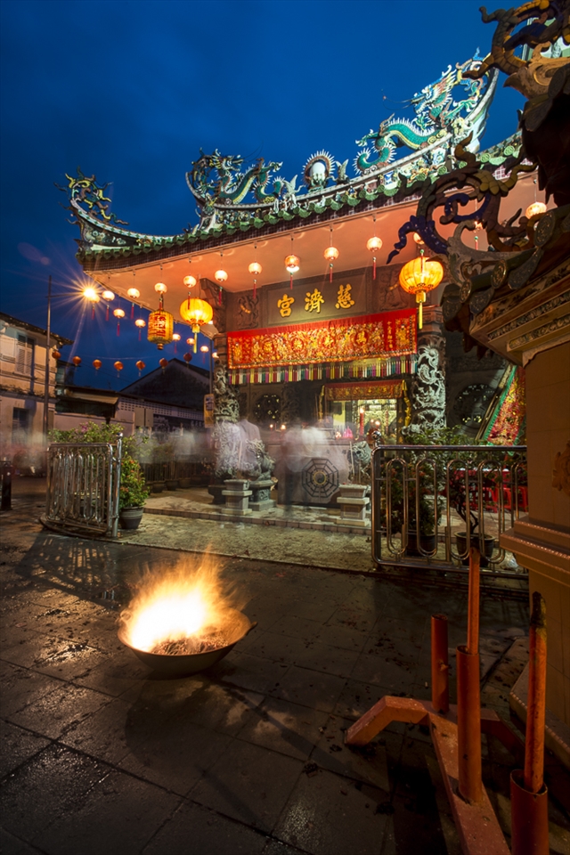 As dusk falls, a lone smouldering drum is the only remaining sign of the day’s earlier frenetic activity outside the Yap clan temple. Late-arriving devotees drift like ghostly spectres as they light their candles, say their prayers and enter the golden glow of the hall under the protective watch of stone dragons and lazy whirls of smoke. The party shows no signs of slowing.