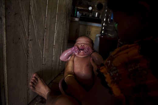A six days old baby with a bath using water from the polluted rivers. Deforestation, coal mining and disposal of industrial waste streams contaminated all. Yet the indigenous has no other alternative sources. In the middle of the water crisis, people are forced to use polluted river water to meet their needs.