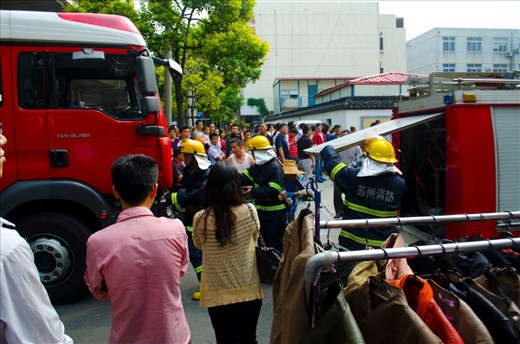 As two firetrucks arrive the firemen quickly jump out and begin preparing their equipment.