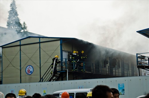 Three of the firemen discuss the situation while another brings the fire-hose.