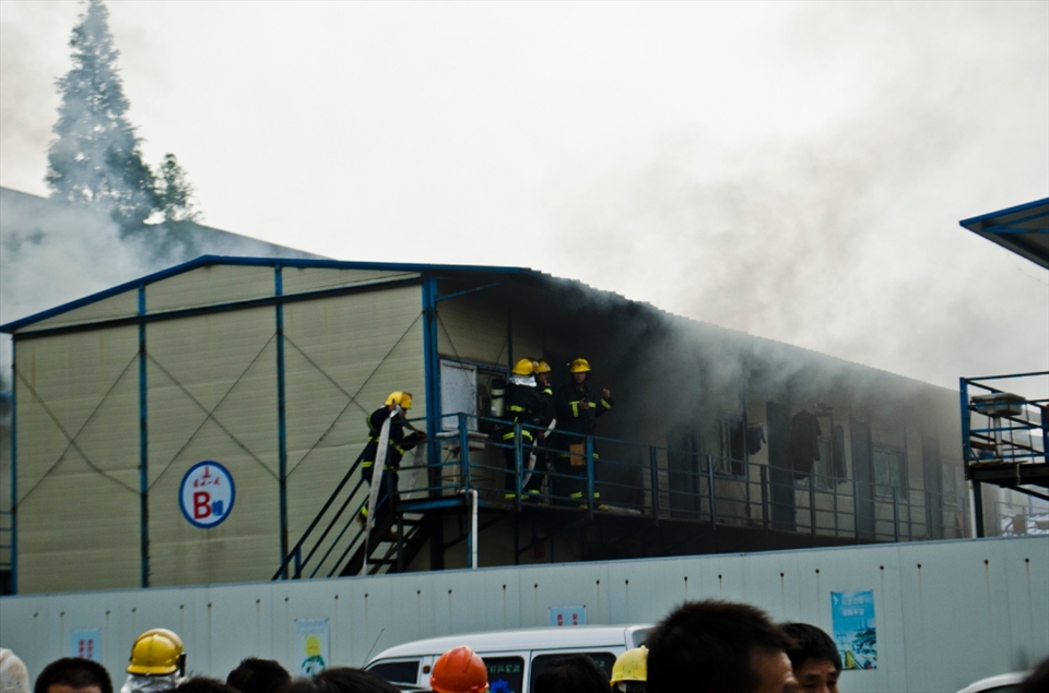 Three of the firemen discuss the situation while another brings the fire-hose.