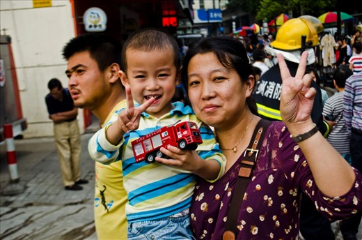 After the situation is under control, a Mother and child holding a toy firetruck pose for the camera. 
