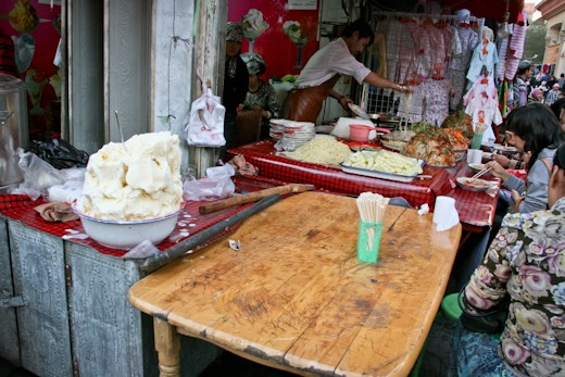 Food is a central part of the Uyghur culture. When Uyghurs meet with friends or family the generally share a meal, and if they don't share a meal they will at least have a snack of some sort. 
This stall was set up in the extreme heat of summer, so they are serving a favorite dish of cold noodles on the right, and on the left, a special treat for dessert or a snack - Uyghur homemade ice cream.