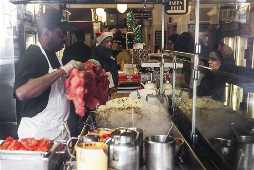 South St & 4th St. South: Jim’s Steak.
Along with the fifty other people standing outside I waited 45 minutes to enter the insanely famous Philly cheese steak establishment. Soon enough I realized that there were another fifty people waiting on the inside. This is outside looking in through the South street window at Jim’s Steak “… since 1939!” Patrons wide eyed and slack jawed stare as another massive side of beef is laid by the man at the beginning of one cheese steaks journey. Right to left the meat is fried gradually on the massive cooktop. Orders are taken, meat and bread come together, condiments are place and beverages are ordered. The staff is a very serious faced group until words are exchanged and slick jokes are offered. The whole experience is a great showing.
