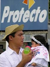 [BREAKING THE STEREOTYPE OF LATINO MALES]
At the Santa Catalina festival I witnessed this moment of dedication and tenderness from a local campesino farmer towards his baby.  He had such focus of care as other men around him were loudly partaking in other activities. I was particularly  struck by the timing of this moment and my reflection of it, as right behind them was a sign 'Protecto' (protection in English). This, I think, may have been a sign for a brand of fertiliser, but nevertheless I found it reflected the essence of the moment and my thoughts around it. During my travels in Panama as a female, I was at times taken aback by macho and chauvinistic attitudes of some men. However, like many countries around the world, it is changing and I was pleased to be get insights into greater open mindedness around gender and associated roles. : by mimosa, Views[682]