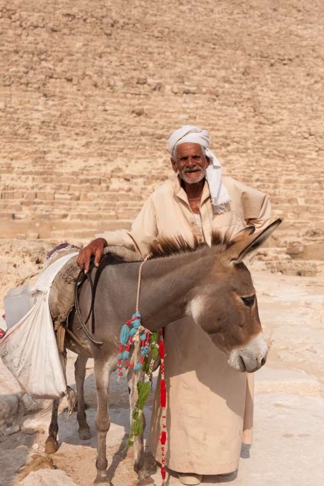 A man and his donkey sell water at the base of the Pyramid of Khufu in Giza.
