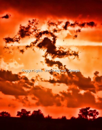 The sky appears to be on fire as the sun sets over the prairie of North Central