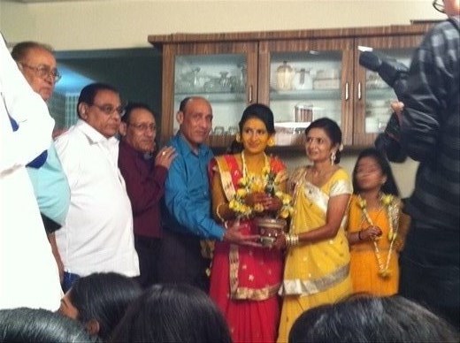 Nital covered with turmeric. Parents on either side. 