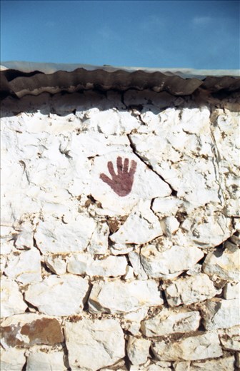 impressed hand on the stone wall. behind the beach