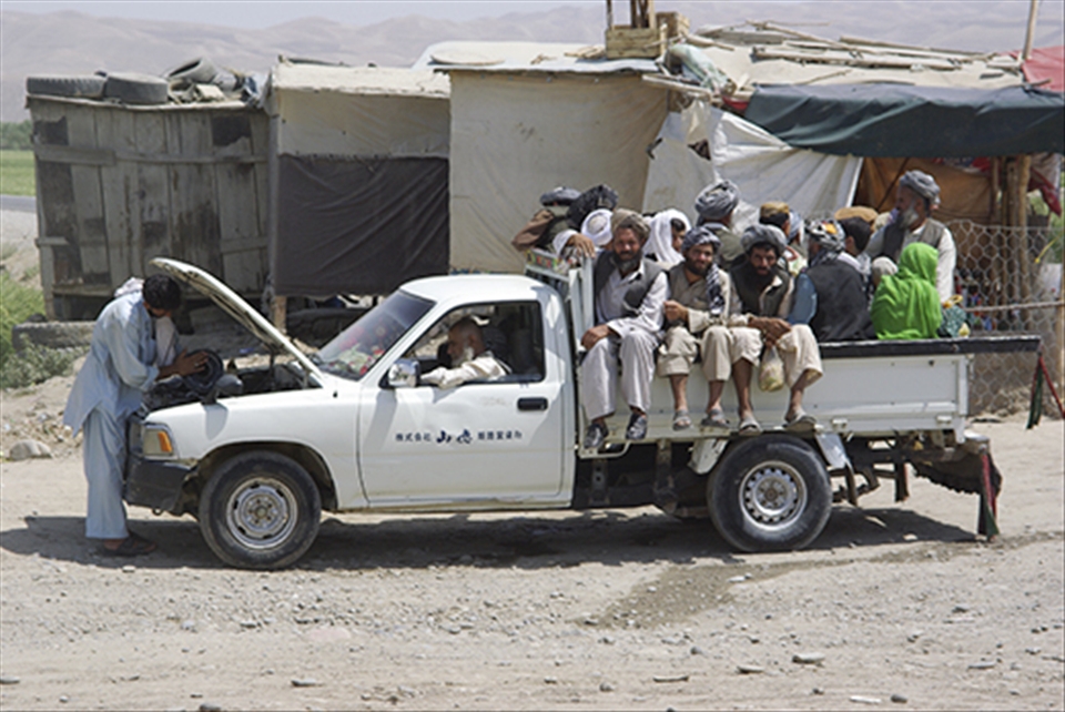 Overheated and overcrowded Japan-donated pick up truck covers the dusty distance.