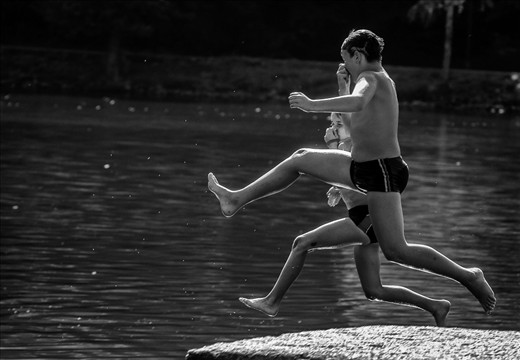 Early autumn: Two boys enjoyng the last days during which the lake's water is not freezing cold , jumping almost  synchronously in the water.