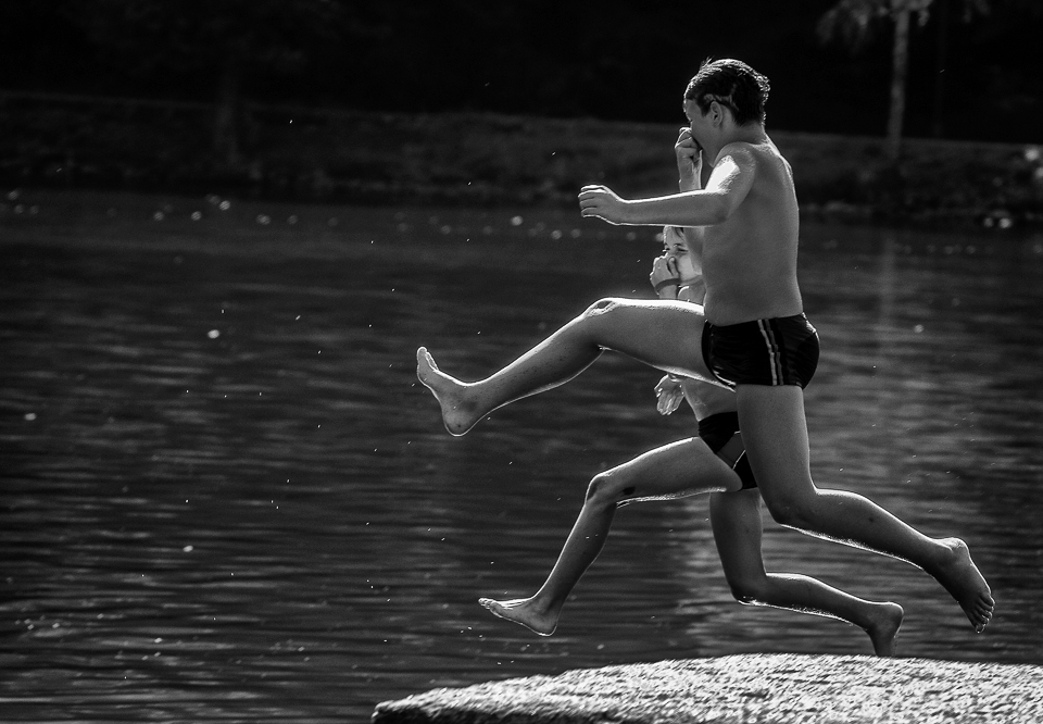 Early autumn: Two boys enjoyng the last days during which the lake's water is not freezing cold , jumping almost  synchronously in the water.