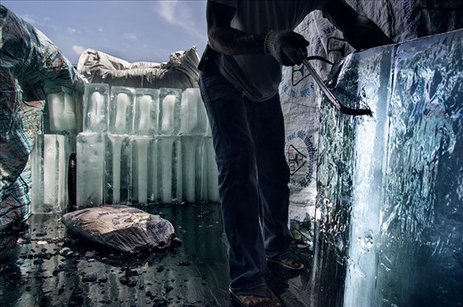 Men unload bricks of ice off a truck to crush up for local families to take home