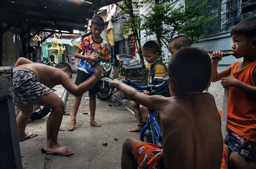 Kids smash clay onto the ground as entertainment, in the ally of the slums
