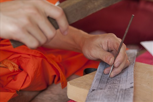 A monk engraves a pattern on a metal plate. This artwork is practiced together with other monks, but also with common believers. These are additional skills monks learn apart from their standard education.
