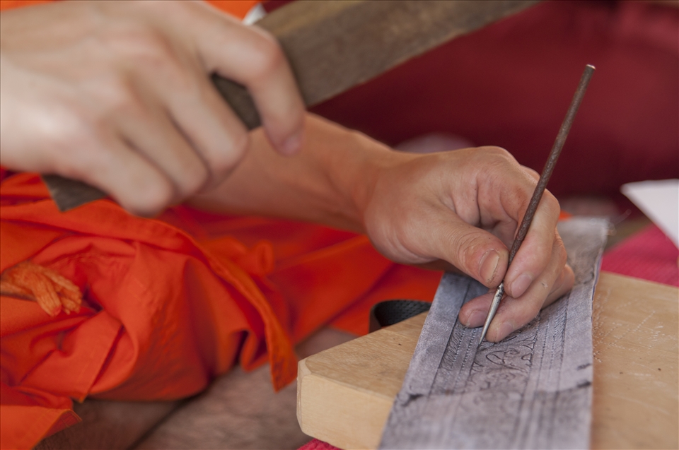 A monk engraves a pattern on a metal plate. This artwork is practiced together with other monks, but also with common believers. These are additional skills monks learn apart from their standard education.