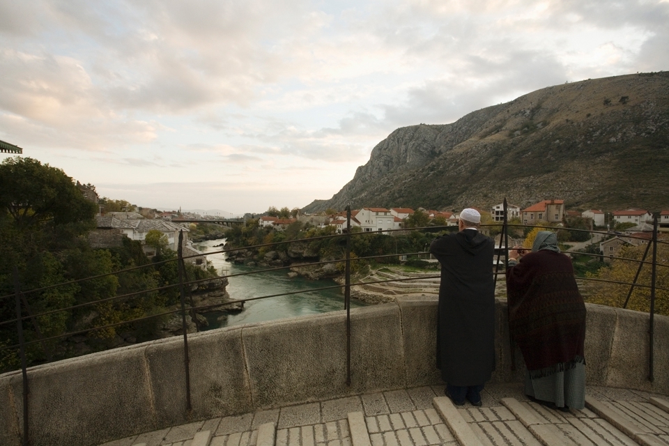 A couple standing on Stari Most Bridge. Stari Most, the connection between the two parts of the city, was destroyed in 1993 during the war after standing for 427 years. It was rebuilt in 2004 and now stands as a major tourist attraction for the city of Mostar.