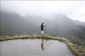 A local girl stands on the rim of a rice field at the top of the mountain, the highest viewpoint over the village. She is holding a wooden walking stick used to navigate along and up and down the slippery edges of the rice fields.: by mountainvillage, Views[326]