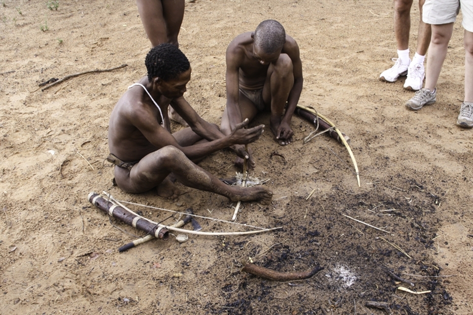 A San shows the traditional way of starting a fire, rubbing 2 sticks together. This is harder than it looks, you must generate enough friction for the tinder to start smouldering. There had been a large storm before this was taken but he had no problems with the wet conditions.