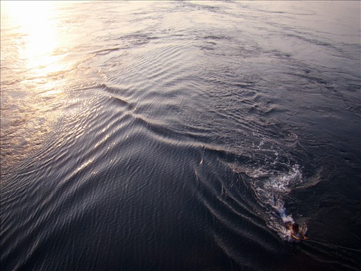 Afternoon swim:a kid feels the waves by hanging to a rope tied to a bridge post.