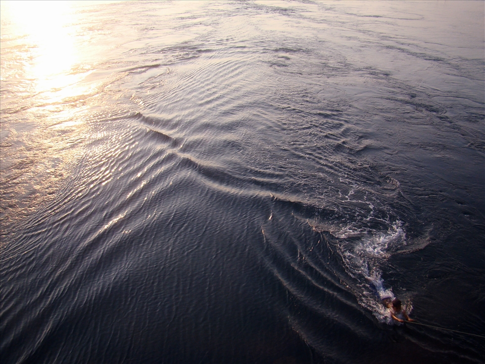 Afternoon swim:a kid feels the waves by hanging to a rope tied to a bridge post.