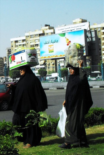 Two strong women in their abayas carrying big crates with no difficulty, in the middle of a busy street in Cairo.